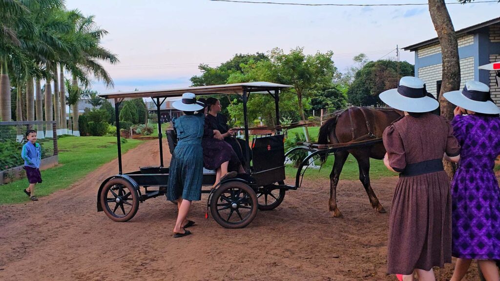 Charrete puxada por cavalos e menonitas com roupas tradicionais em Nueva Durango, Paraguai.